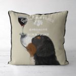Bernese dog with a glass of red wine balanced on his nose.