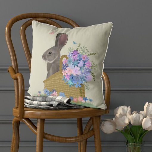 Pillow with a grey bunny sitting in a basket with pink and blue flowers. Set view.