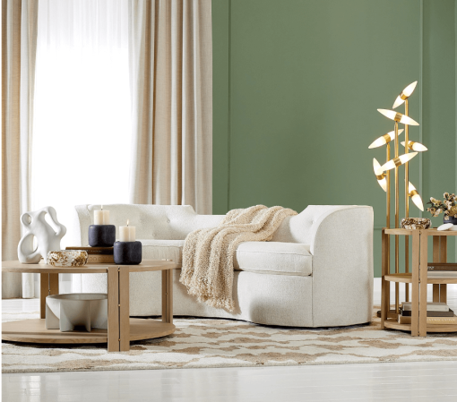 Lauren sofa in cream color, lifestyle photo. A curvaceous shape, bench seat cushion, and button-tufted detail.