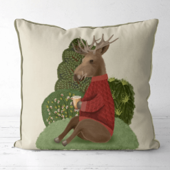 This is a pillow that features a moose design in a red sweater sitting on a hill enjoying a cup of cider.