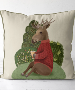 This is a pillow that features a moose design in a red sweater sitting on a hill enjoying a cup of cider.