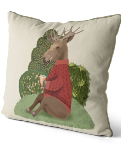 This is a pillow that features a moose design in a red sweater sitting on a hill enjoying a cup of cider.