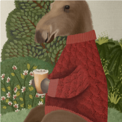 This is a pillow that features a moose design in a red sweater sitting on a hill enjoying a cup of cider.