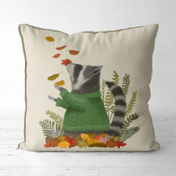 A pillow that displays a raccoon in a green sweater playing in fall leaves.