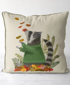 A pillow that displays a raccoon in a green sweater playing in fall leaves.