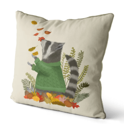 A pillow that displays a raccoon in a green sweater playing in fall leaves.