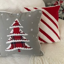 Christmas Tree with plaid fabric and snow tipped edges, on grey fabric with other pillows.
