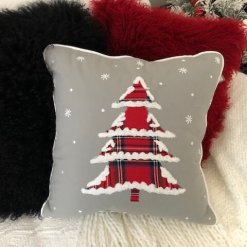 Christmas Tree with plaid fabric and snow tipped edges, on grey fabric with other pillows.