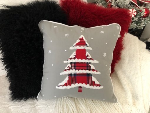 Christmas Tree with plaid fabric and snow tipped edges, on grey fabric with other pillows.