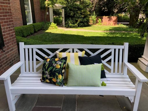 Lemons and green woven pillows shown on front porch bench